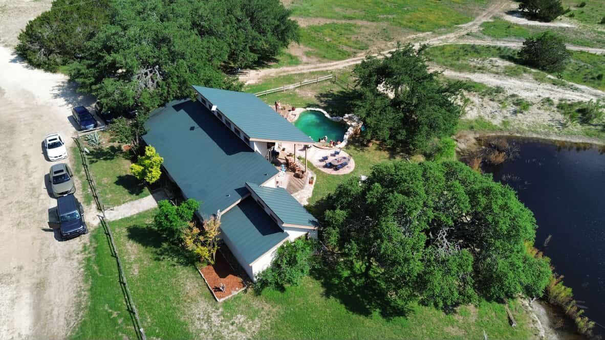 Aerial of ranch house, pool and grotto beside the pond