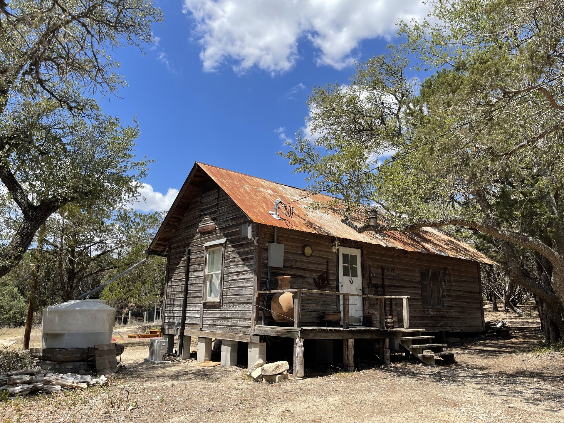 Weathered homestead cabin with rusted tin roof under live oaks